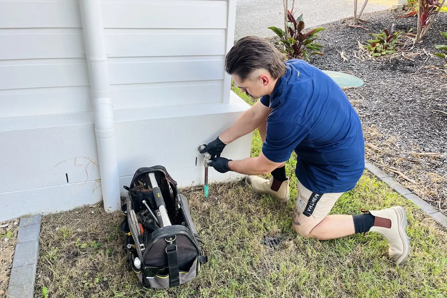 Qualified Plumber outside a home closing the main gas shut-off valve prior to maintenance. High Tide Plumbing on the Gold Coast