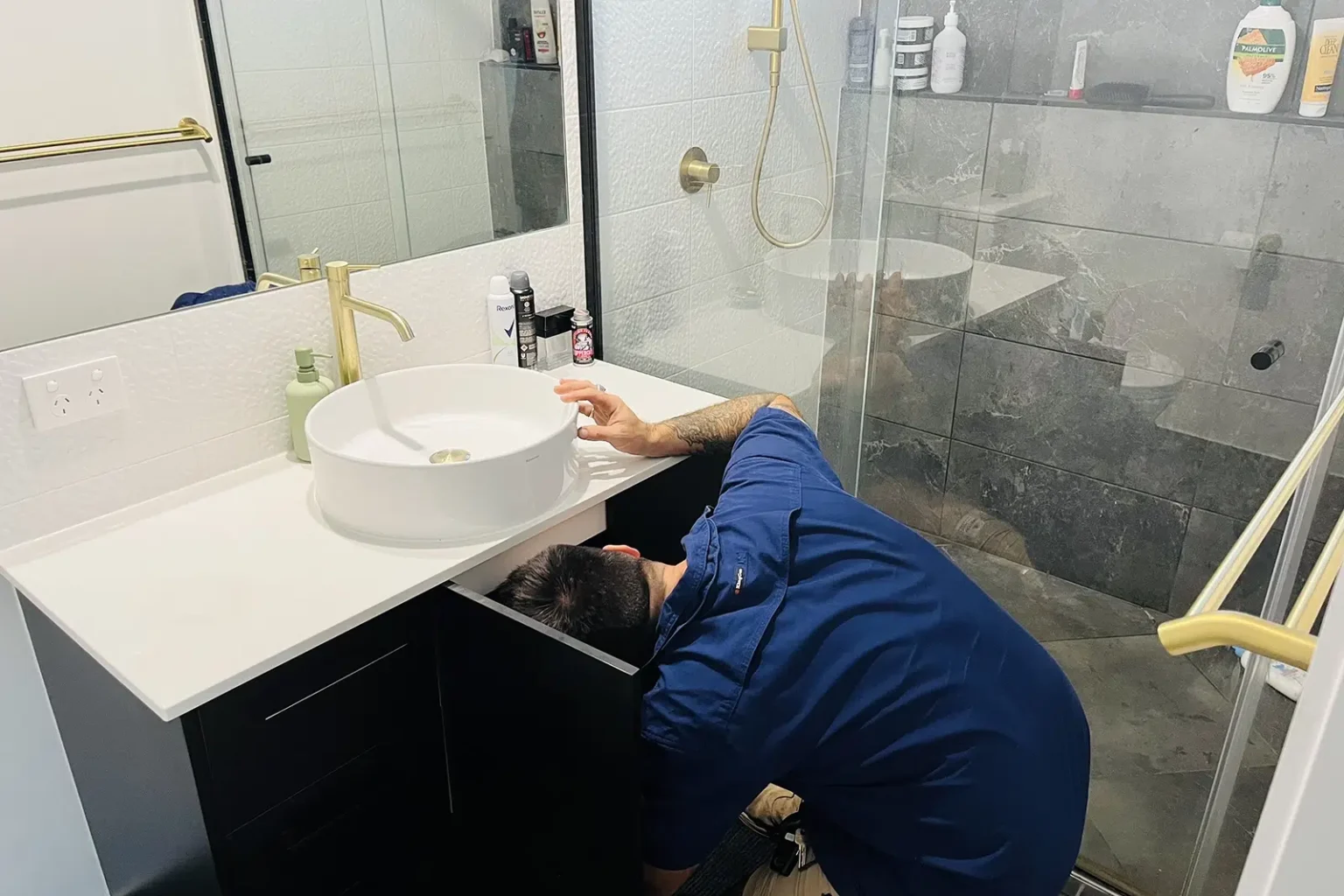 A Professional Plumber with his head under a sink for moisture. Leak Detection on The Gold Coast - High Tide Plumbing & Gas Gold Coast