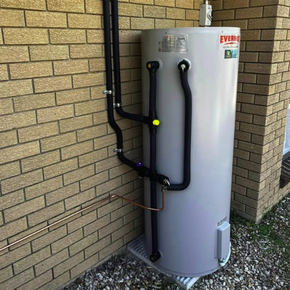Grey Gas Hot water service on a steel grate outside a house. High Tide Plumbing & Gas