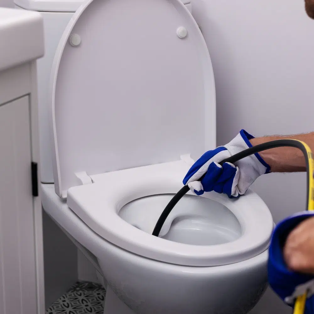 A qualified plumber performs a toilet blockage clearing with pipes inserted into the toilet