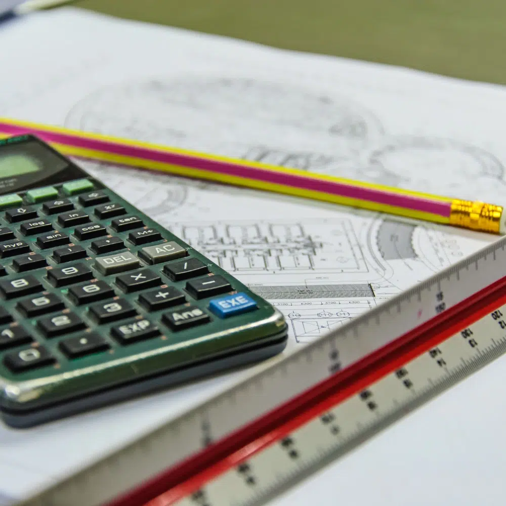 A calculator, pencil and plans for a leak detection cost estimate to send to a home owners
