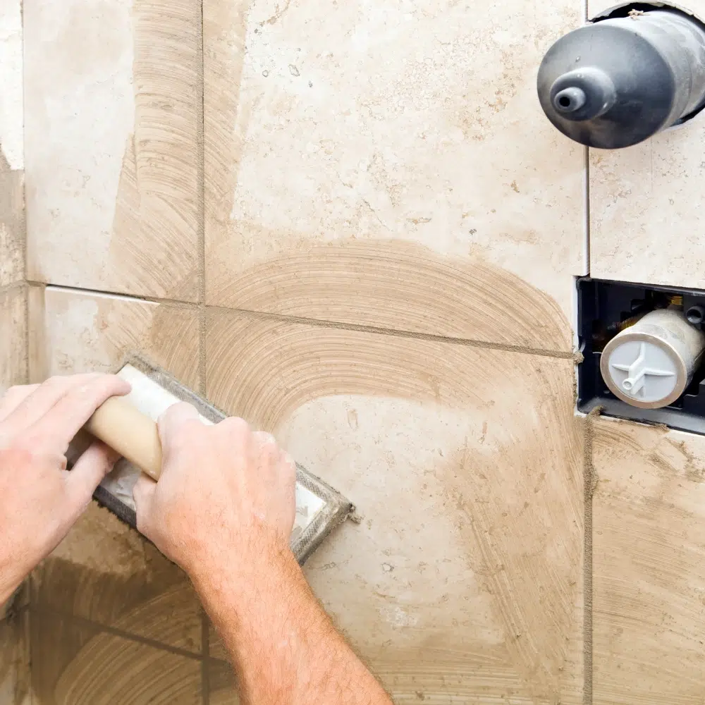 A High Tide Plumber grouts tiles as repairs to the shower base in a Gold Coast home