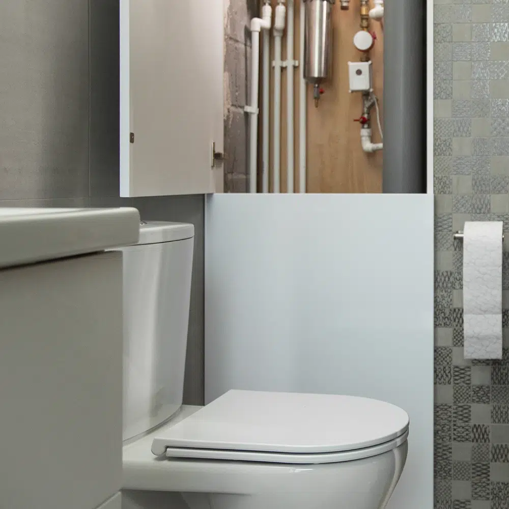 An opened cupboard revels plumbing pipes as part of preventative toilet maintenance on the Gold Coast