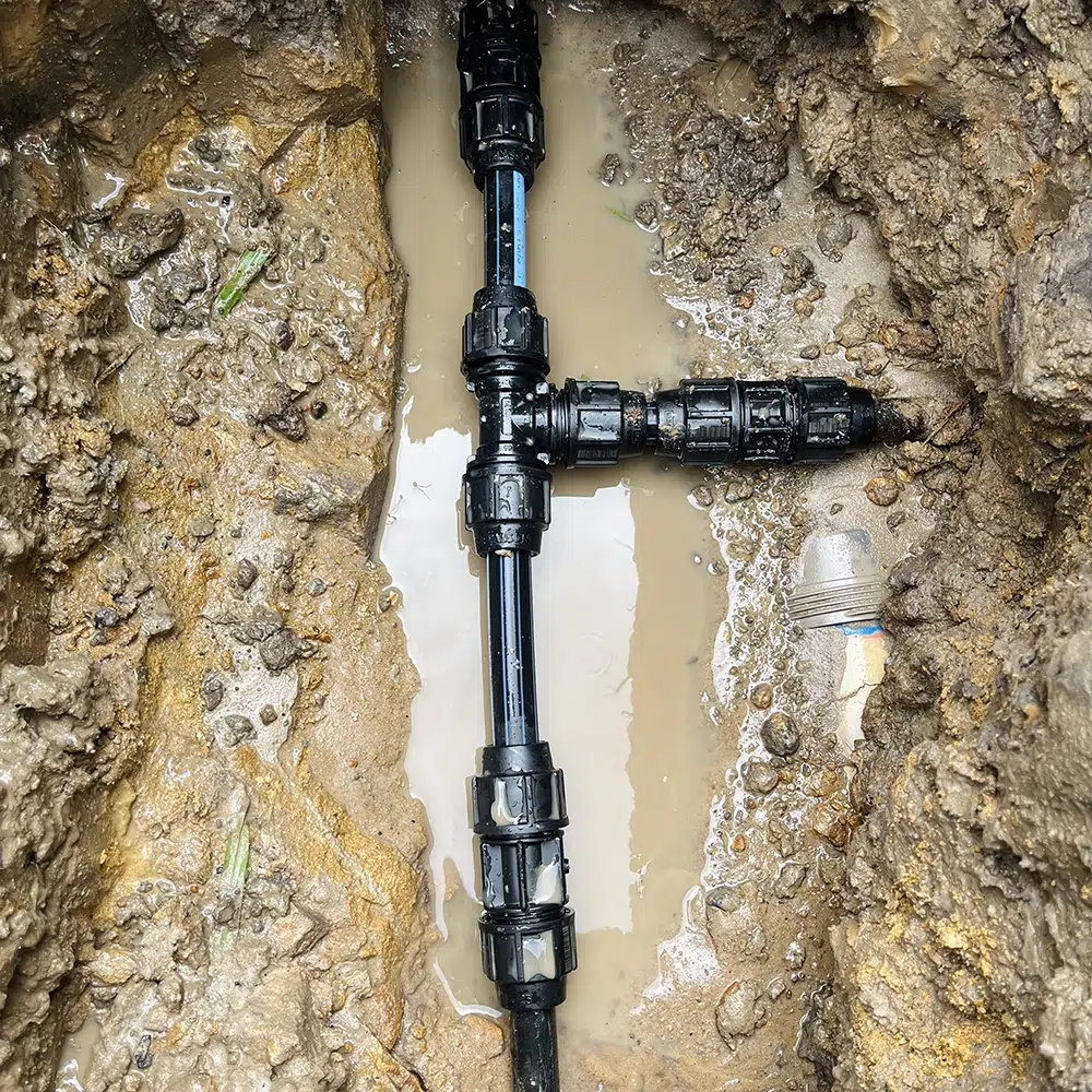 Black plastic leaking and burst pipes on the Gold Coast have been excavated in a water filled hole as a burst pipe outdoors