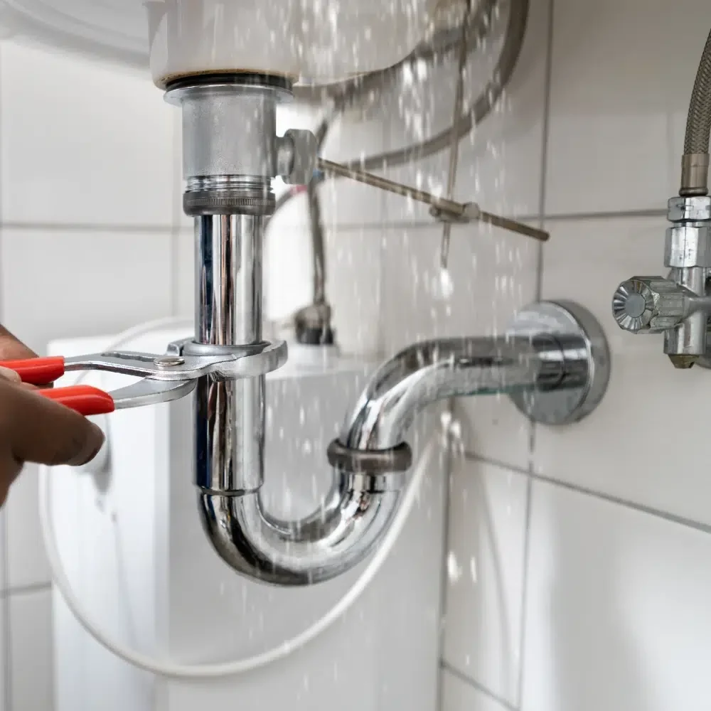 An experienced and licenced plumber under a kitchen sink providing Professional Pipe Leak Services across the Gold Coast